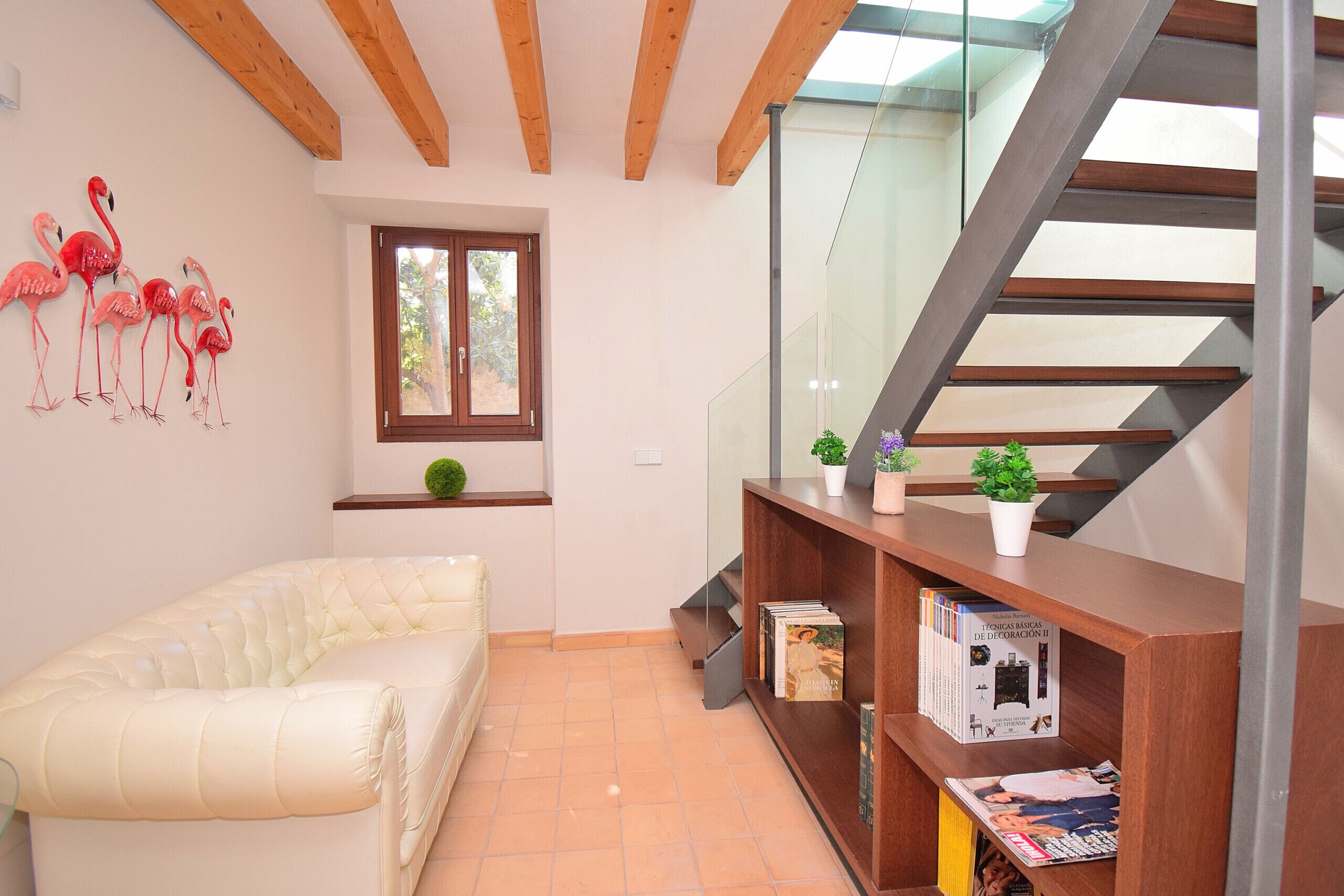 Una habitación con una cama, una ventana, una estantería y una escalera.