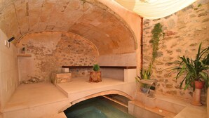 A stone-walled room with a small pool, a wooden bench, and potted plants. - 252 Casa Alcariot VT/107415 by Mallorca Charme (Arta)