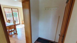 Ein Zimmer mit Fliesenboden, Holzboden und einer Tür zu einem weiteren Raum.