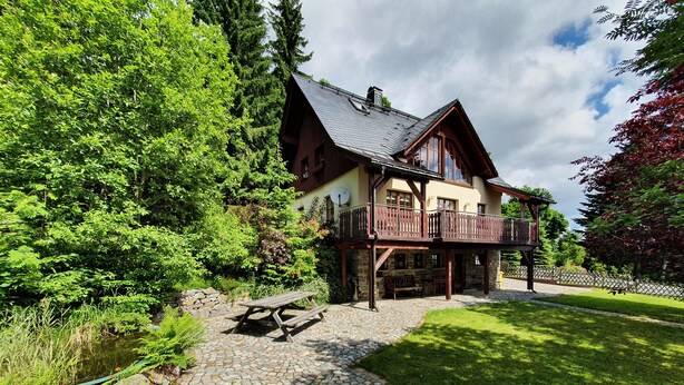 Ein Chalet mit einer Steinterrasse, einer Holzterrasse und einem Picknicktisch.