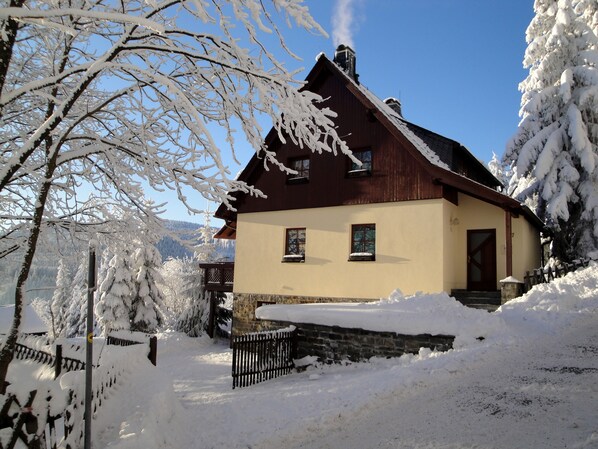 A snow-covered house with a wooden facade and a stone foundation.