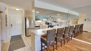 A modern kitchen with a central island, built-in appliances, and a dining area with six wicker chairs. - Sun-Dappled PCB Retreat w/ Multiple Pools! (Panama City Beach)