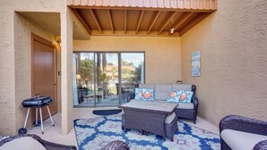 A covered patio area with a wicker sofa, a table, and a grill. - Sun-Dappled PCB Retreat w/ Multiple Pools! (Panama City Beach)