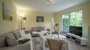 Ett vardagsrum med en soffa, ett soffbord, en tv och ett stort fönster.