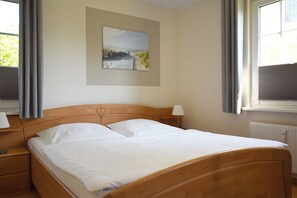 Relax in a serene space with a comfortable bed, a beautiful painting, and a window with curtains.