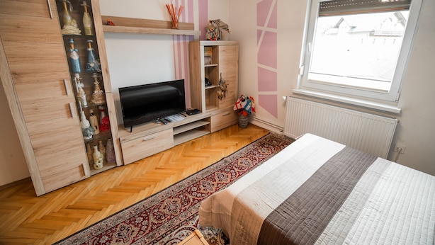 A bedroom with a bed, a TV, a wardrobe, a window, and a patterned rug. - Apartment Carmen (Radovljica)
