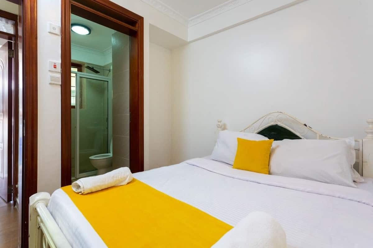A hotel room with a bed, a bathroom, and a door.