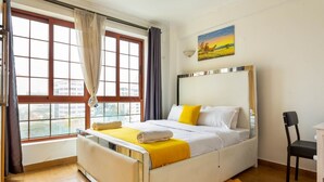 Un dormitorio con una cama, una silla, un escritorio y una ventana con cortinas.