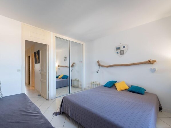 A bedroom with a bed, a wardrobe, a mirror, and a small bedside table.