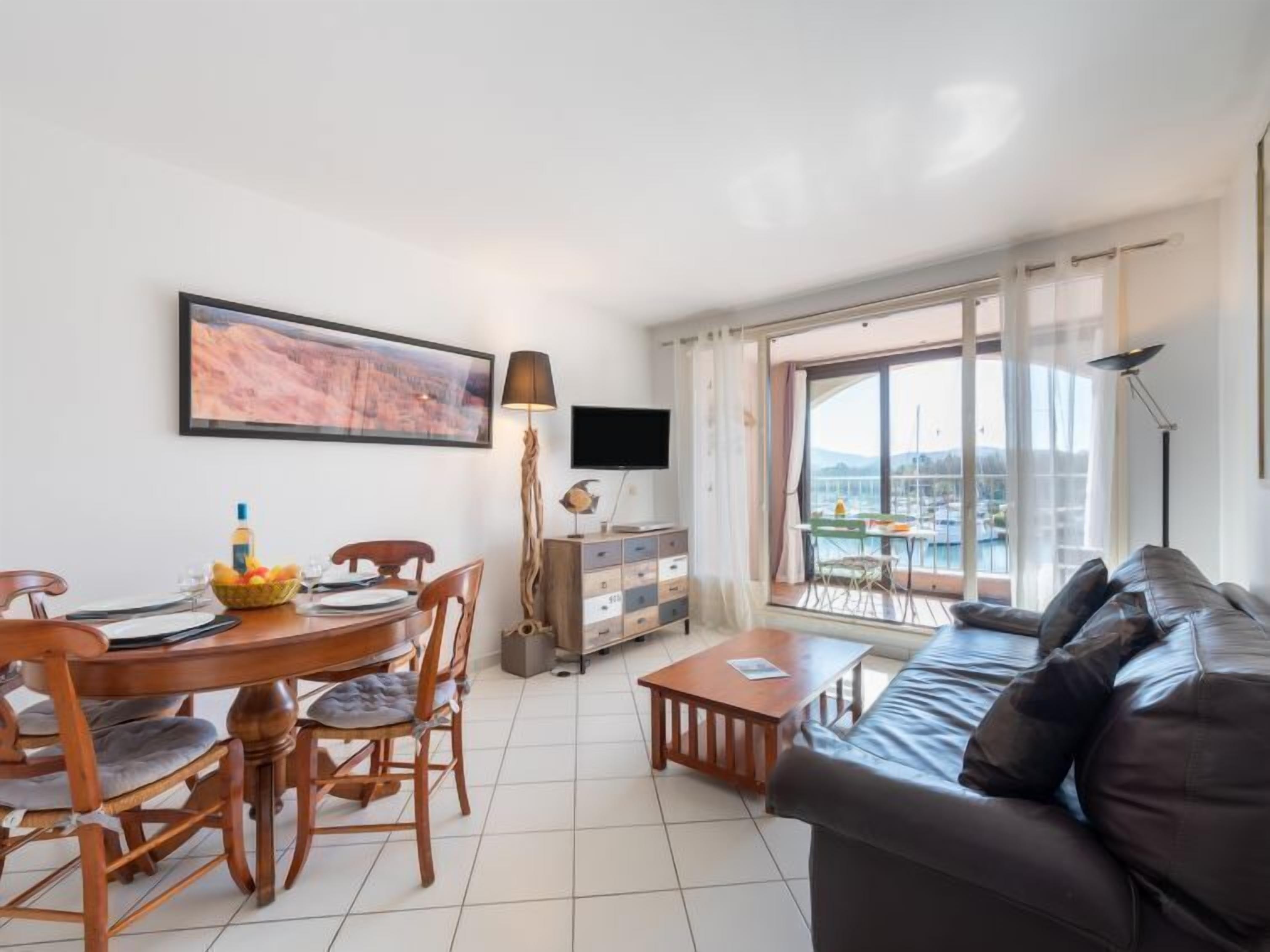 A living room with a dining area, a sofa, a TV, and a large window with a view.