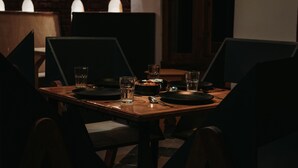 Mesa para cuatro personas dispuesta con sillas, vasos y un frutero.