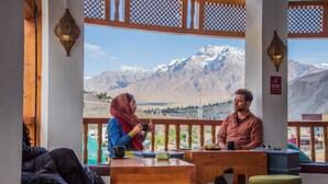 Un rincón acogedor con mesa y bancos de madera, con vistas a un paisaje montañoso.