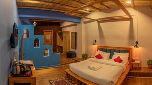 Un dormitorio con cama de madera, paredes azules y pared de ladrillo.