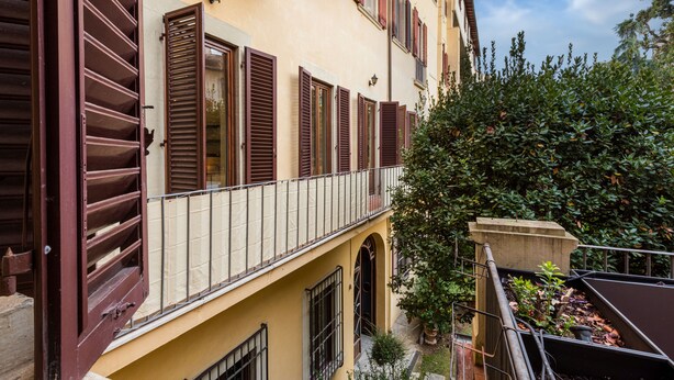 A building with multiple balconies, a garden area with potted plants, and a clear sky. - Duomo Luxury House by Mmega (Florence)