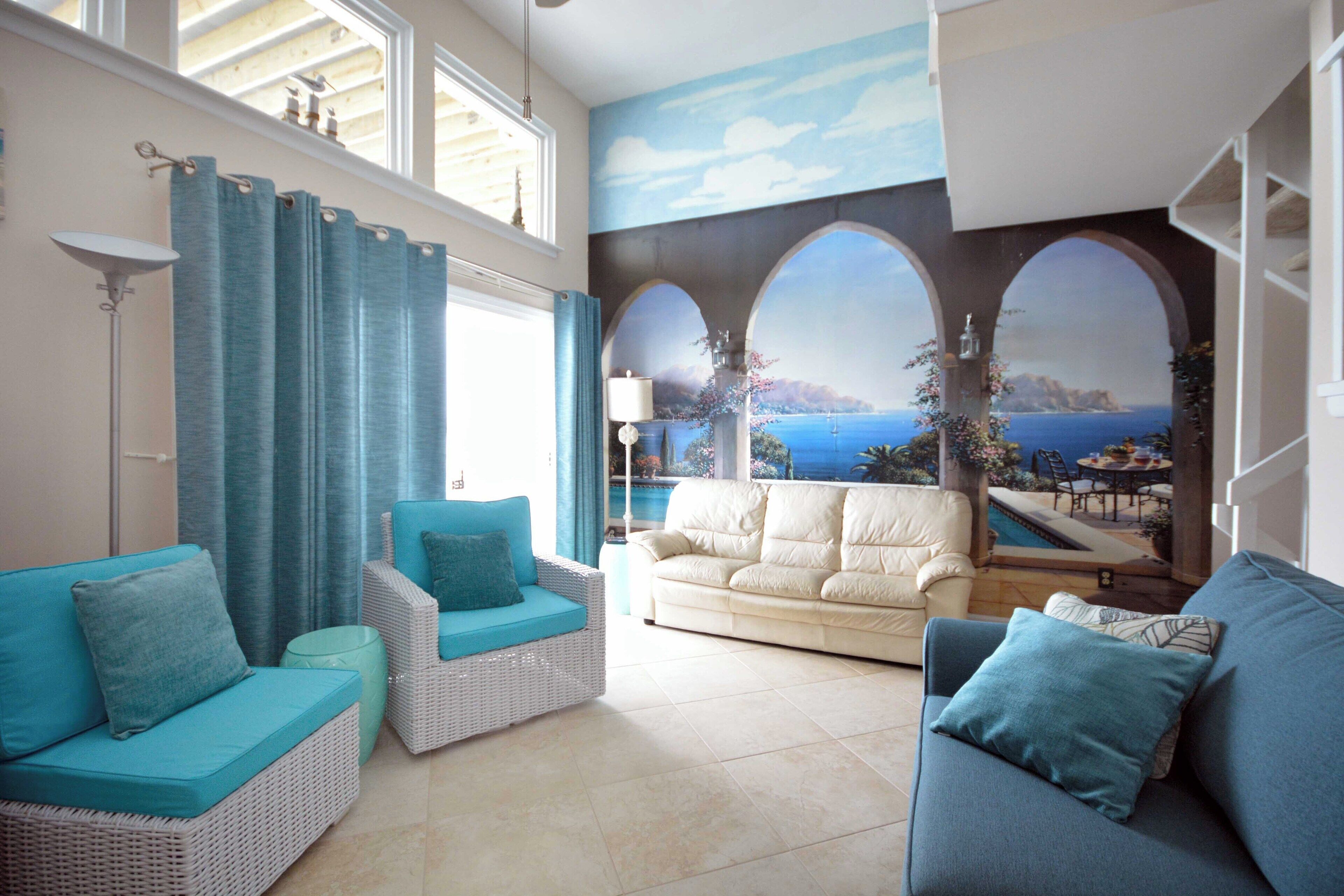 A living room with two sofas, a floor lamp, and a view of the sea through a mural.