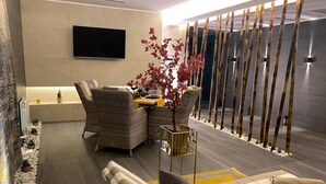 A modern living room with a sofa, chairs, a coffee table, and a TV mounted on the wall.