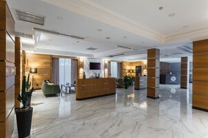 Un moderno vestíbulo de hotel con una recepción, una zona de estar y un amplio ventanal.
