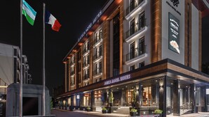 A modern hotel building with a sign reading "Aegea Hotel Suites".