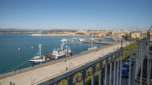 Un puerto con barcos amarrados, un paseo marítimo y un paisaje urbano al fondo.