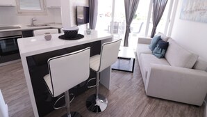 A modern living space with a kitchen, dining area, and a sofa. - Apartments & Rooms Danivan Pool Villas B (Novalja)