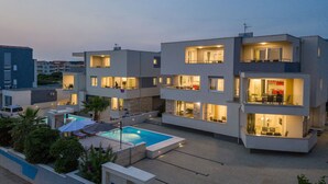 A modern multi-story residential building with a swimming pool, outdoor seating, and balconies. - Apartments & Rooms Danivan Pool Villas B (Novalja)