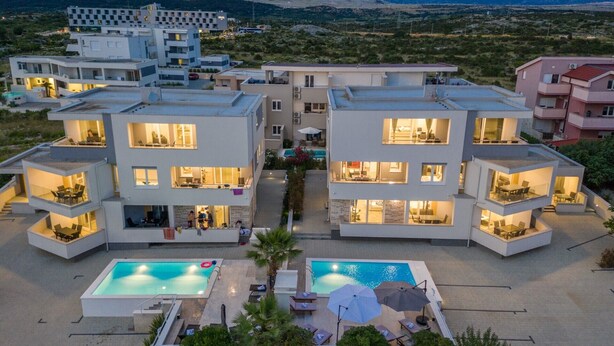 A modern multi-story residential building with balconies, a swimming pool, and a view of the surrounding landscape. - Apartments & Rooms Danivan Pool Villas B (Novalja)