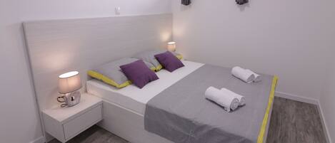 Un dormitorio moderno con una cama grande, lámparas de noche, un cuadro en la pared y una ventana con cortinas.