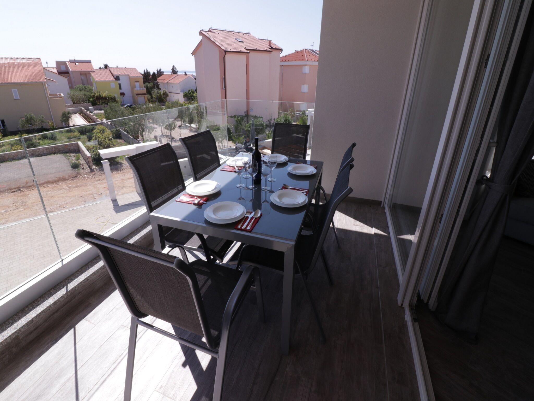 En balkong med ett matbord för fyra personer, stolar och ett glasräcke.