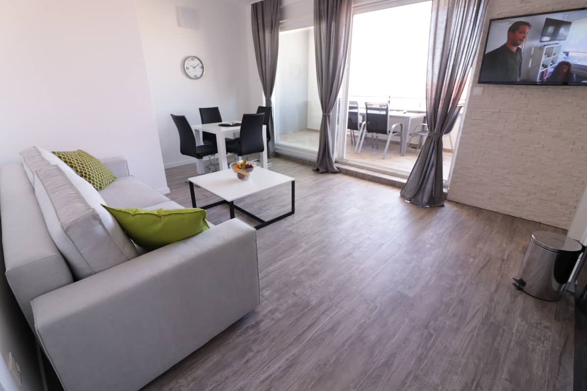 A modern living room with a sofa, coffee table, and dining area.