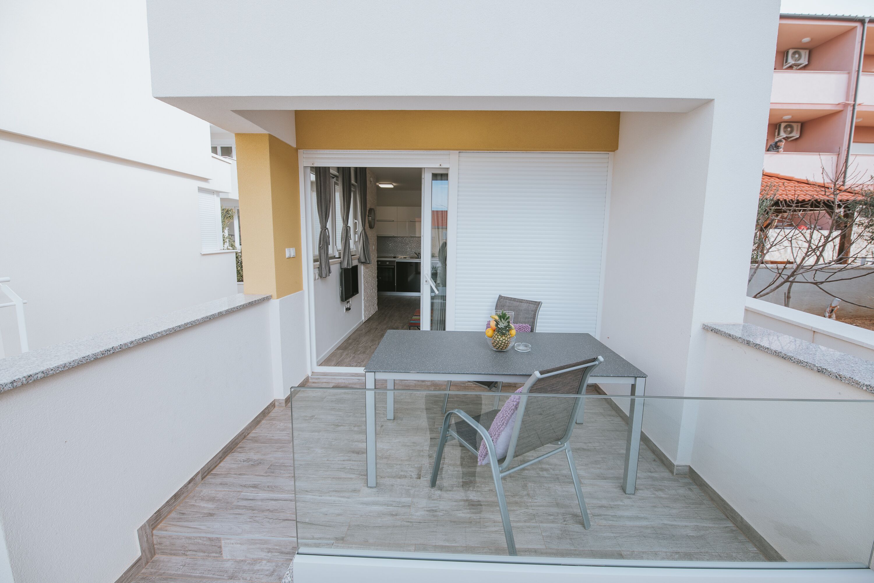 A balcony with a table and chairs, a sliding door, and a view of a building with balconies.