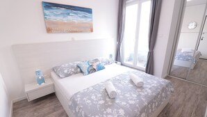A bedroom with a bed, a nightstand, a painting, and a window with curtains. - Apartments & Rooms Danivan Pool Villas B (Novalja)