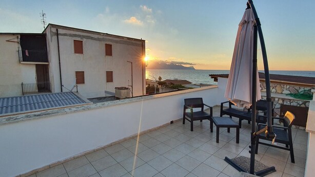 A rooftop terrace with a view of the sea at sunset, featuring a table and chairs, a pergola, and a railing. - View of the gulf of castellammare mountains and beach (Alcamo Marina)