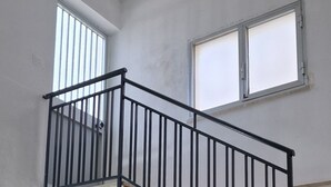 A staircase with black railings and beige steps. There are two windows with white frames on the walls. - View of the gulf of castellammare mountains and beach (Alcamo Marina)