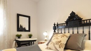 A neatly arranged bedroom with a bed, bedside table, lamp, and a mirror on the wall. - Vacation home Arenal by Interhome (L'Ampolla)
