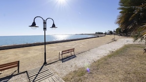 A beach with a wooden walkway, benches, and a street lamp. - Vacation home Arenal by Interhome (L'Ampolla)