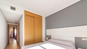A bedroom with a bed, a nightstand, a wardrobe, and a hallway leading to another room. - Lomas del Mar V by Interhome (Vera)