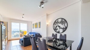 A modern living room with a dining area, large windows, and a balcony. - Lomas del Mar V by Interhome (Vera)