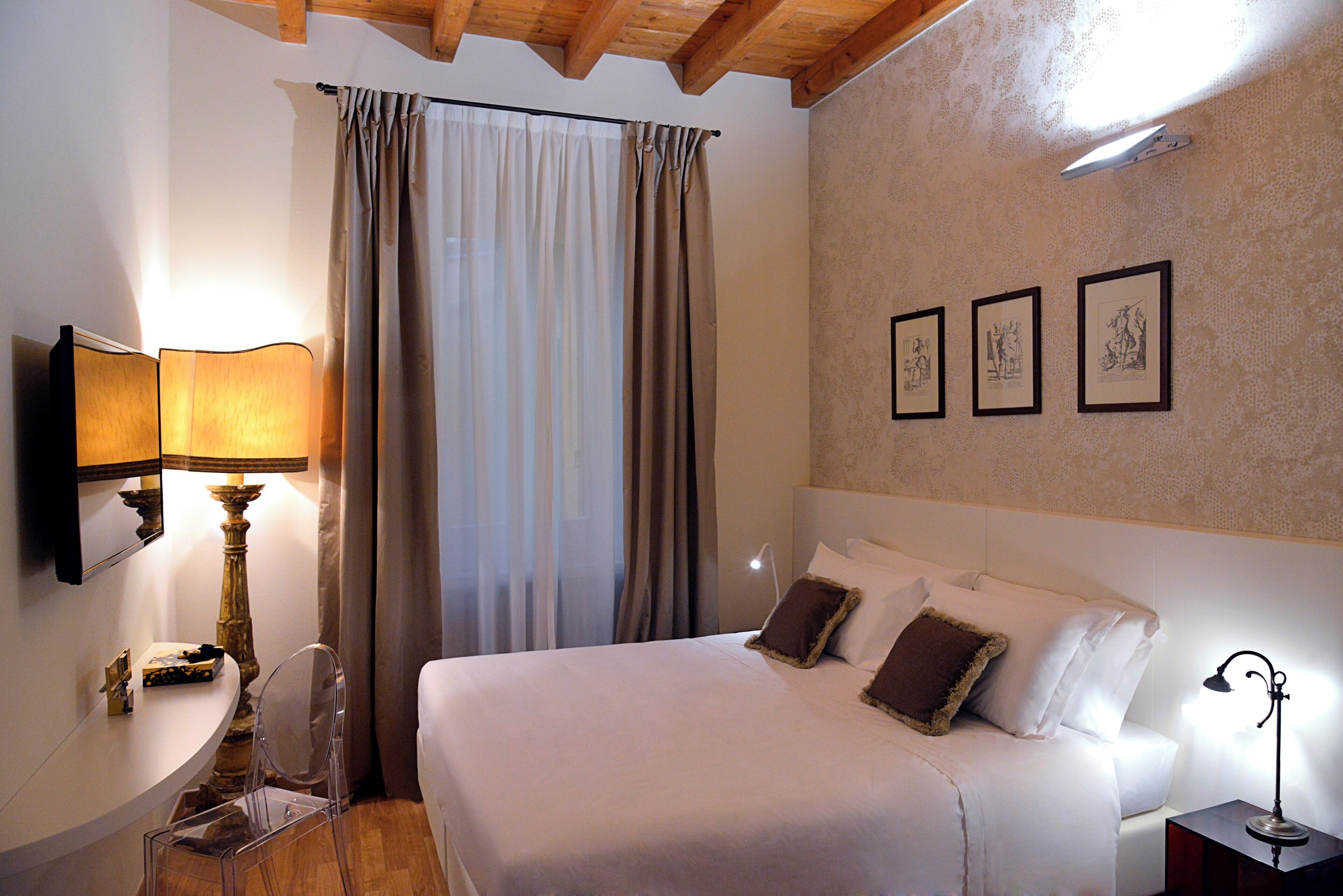 A neatly arranged hotel room with a bed, bedside table, lamp, and a mirror.
