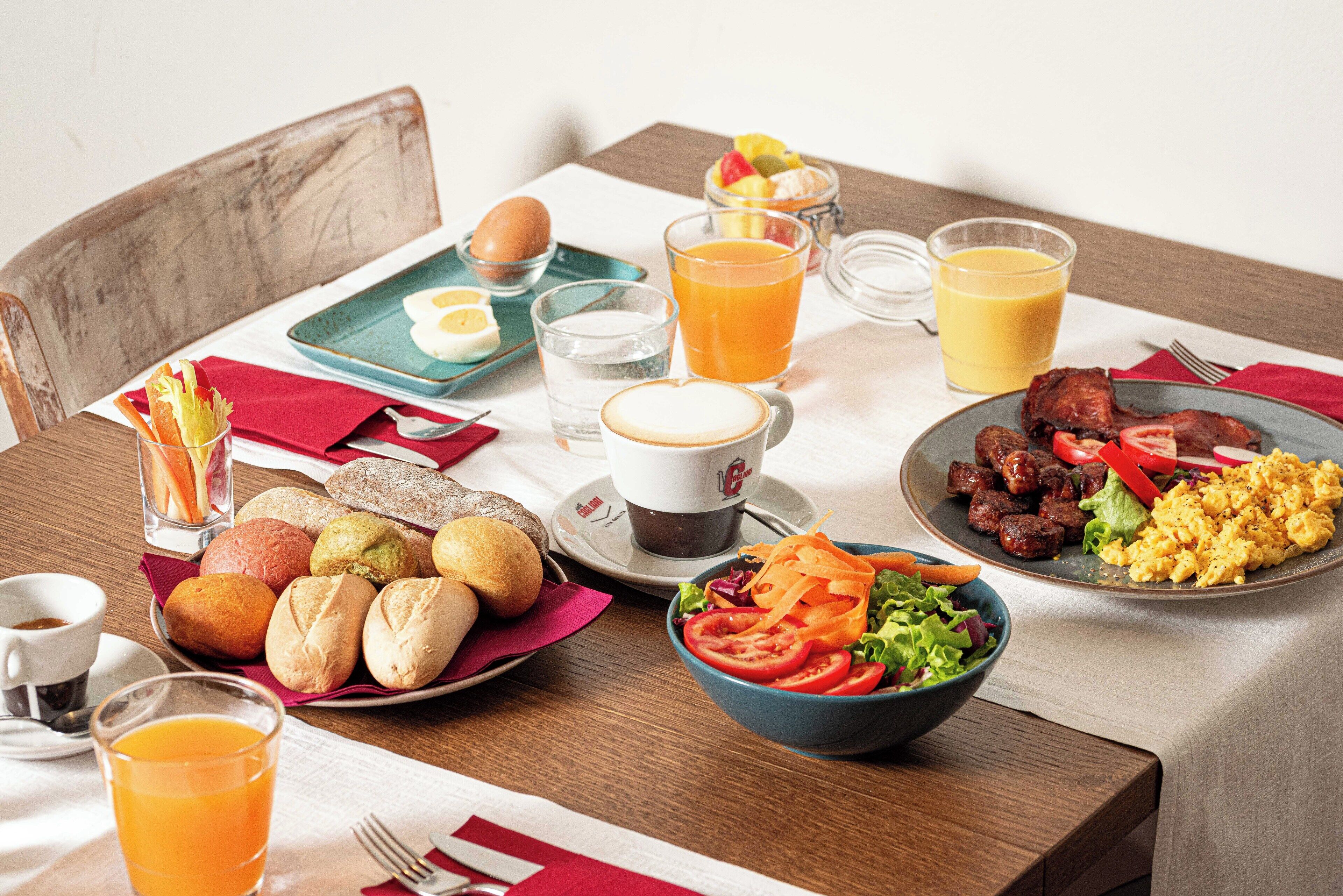Une table dressée pour le petit-déjeuner, avec différents plats, des boissons et une tasse de café.
