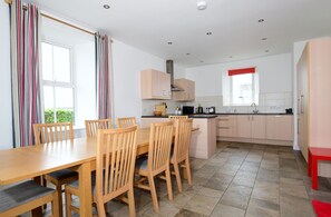 Eine moderne Küche mit Holzausbau, einer zentralen Kochinsel und einem Essbereich mit Holzbänken.