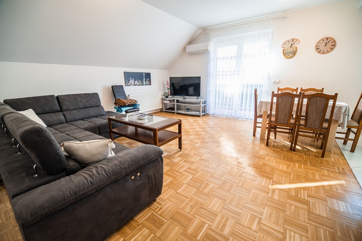 A living room with a sofa, coffee table, TV, and dining area with chairs and a table.