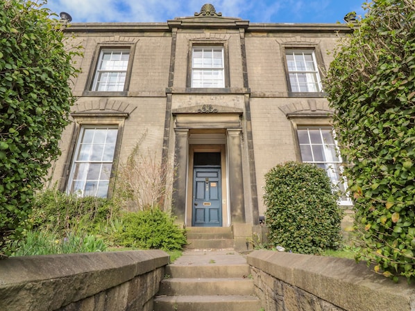 A two-story building with a central entrance, flanked by symmetrical windows and a decorative cornice.