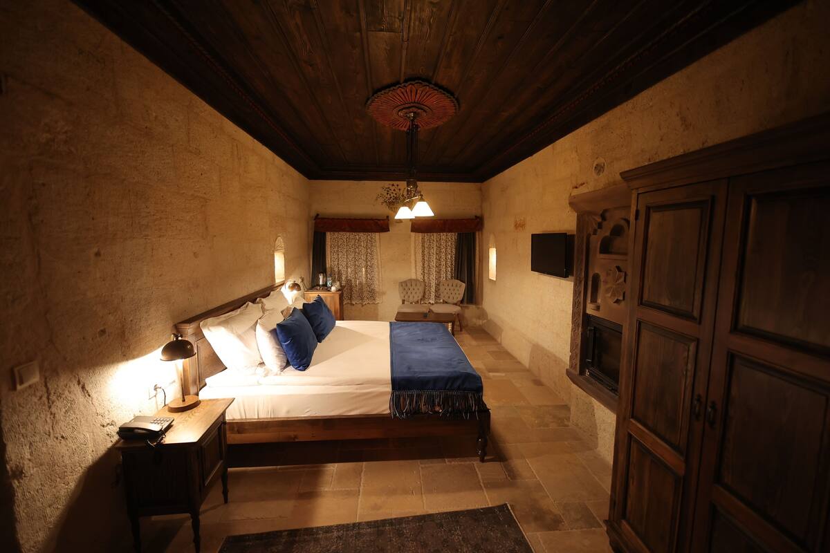 A bedroom with a wooden bed, a nightstand, a desk, a chair, and a wardrobe.