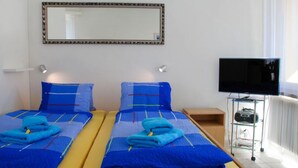 Ett hotellrum med två sängar, en tv och en spegel på väggen.