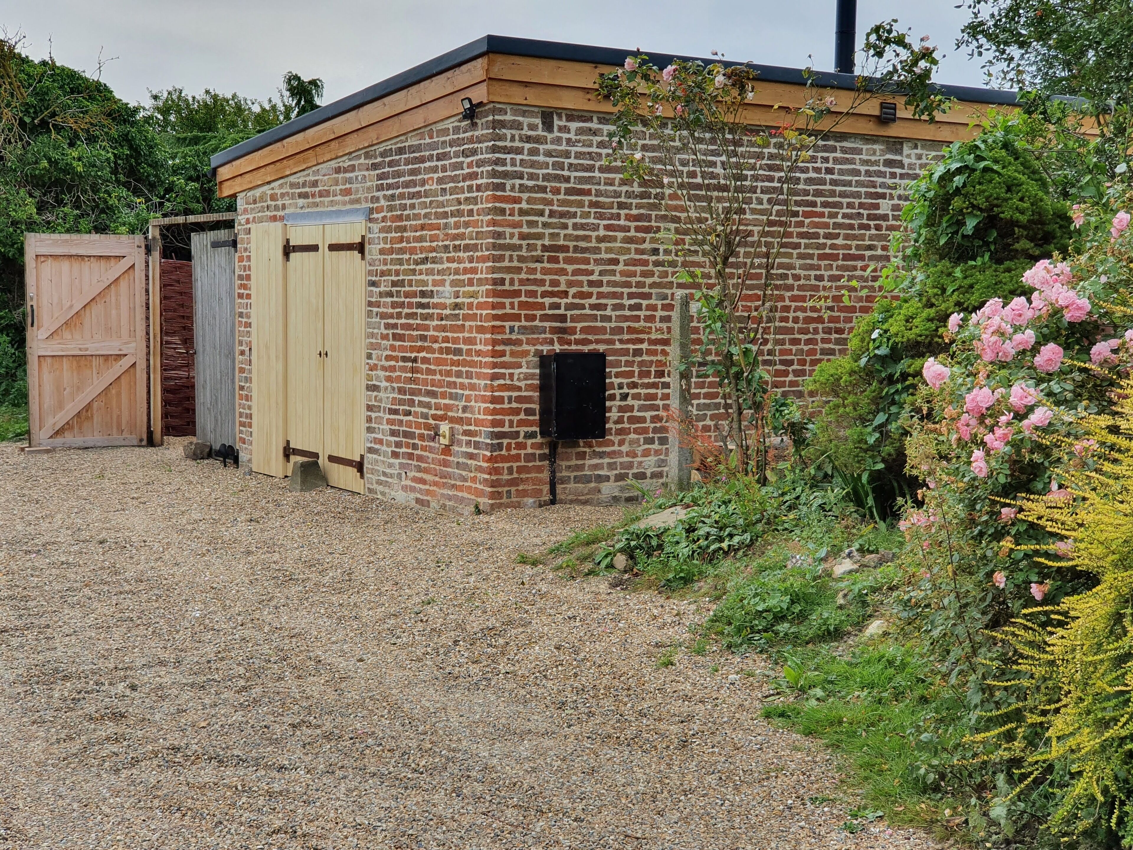 A brick building with a wooden door and a small black box on the wall.
