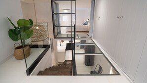 A modern interior with a glass staircase leading to a bedroom. - Freya: Apartment in the center of the village (L'Escala)
