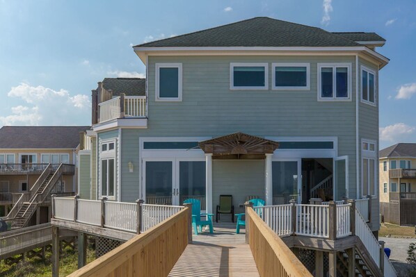 A two-story house with a balcony, a covered entryway, and a deck with chairs. - @ The Beach - 7BR Oceanfront Home in Hampton Colony (North Topsail Beach)