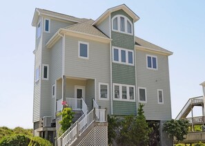 A multi-story residential building with a central staircase, multiple windows, and a visible address number. - @ The Beach - 7BR Oceanfront Home in Hampton Colony (North Topsail Beach)