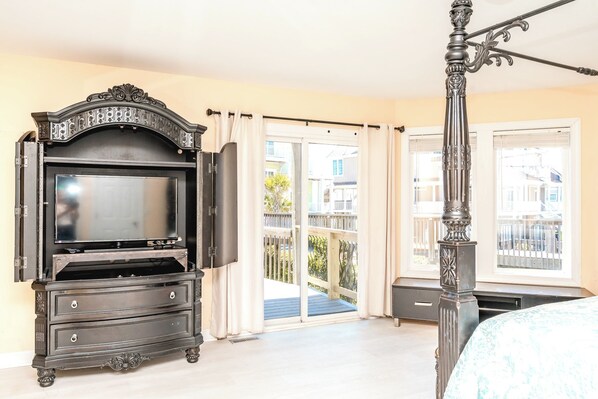 A bedroom with a four-poster bed, a dresser, and a television. - @ THE PEACH offers an escape to an oceanfront/oceanside (North Topsail Beach)