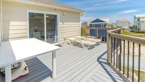 A deck with a table and chairs, a sliding glass door leading to a room, and a view of neighboring houses.